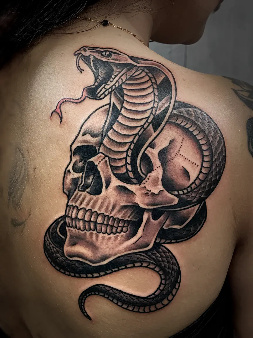 Cobra emerging from skull back tattoo
