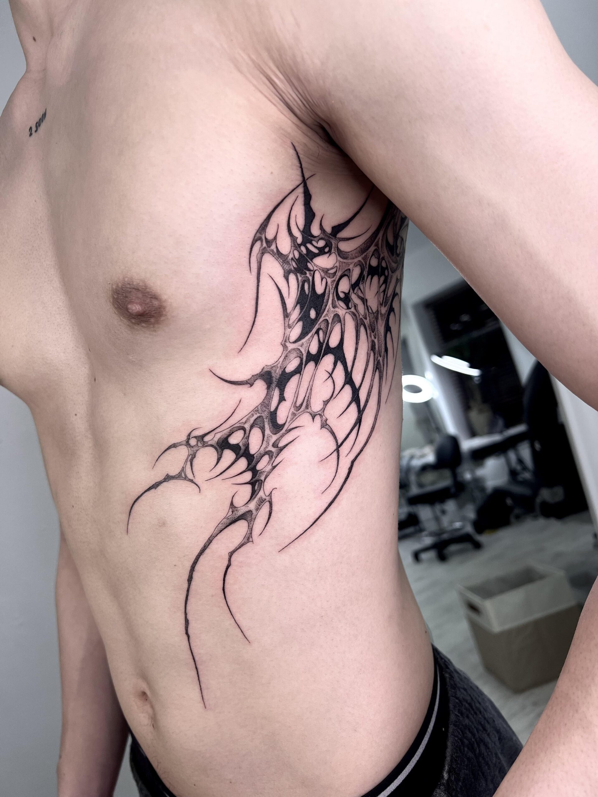 Sharp neo-tribal rib cage tattoo design