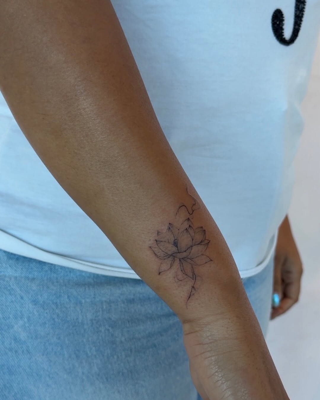 Delicate lotus flower wrist tattoo