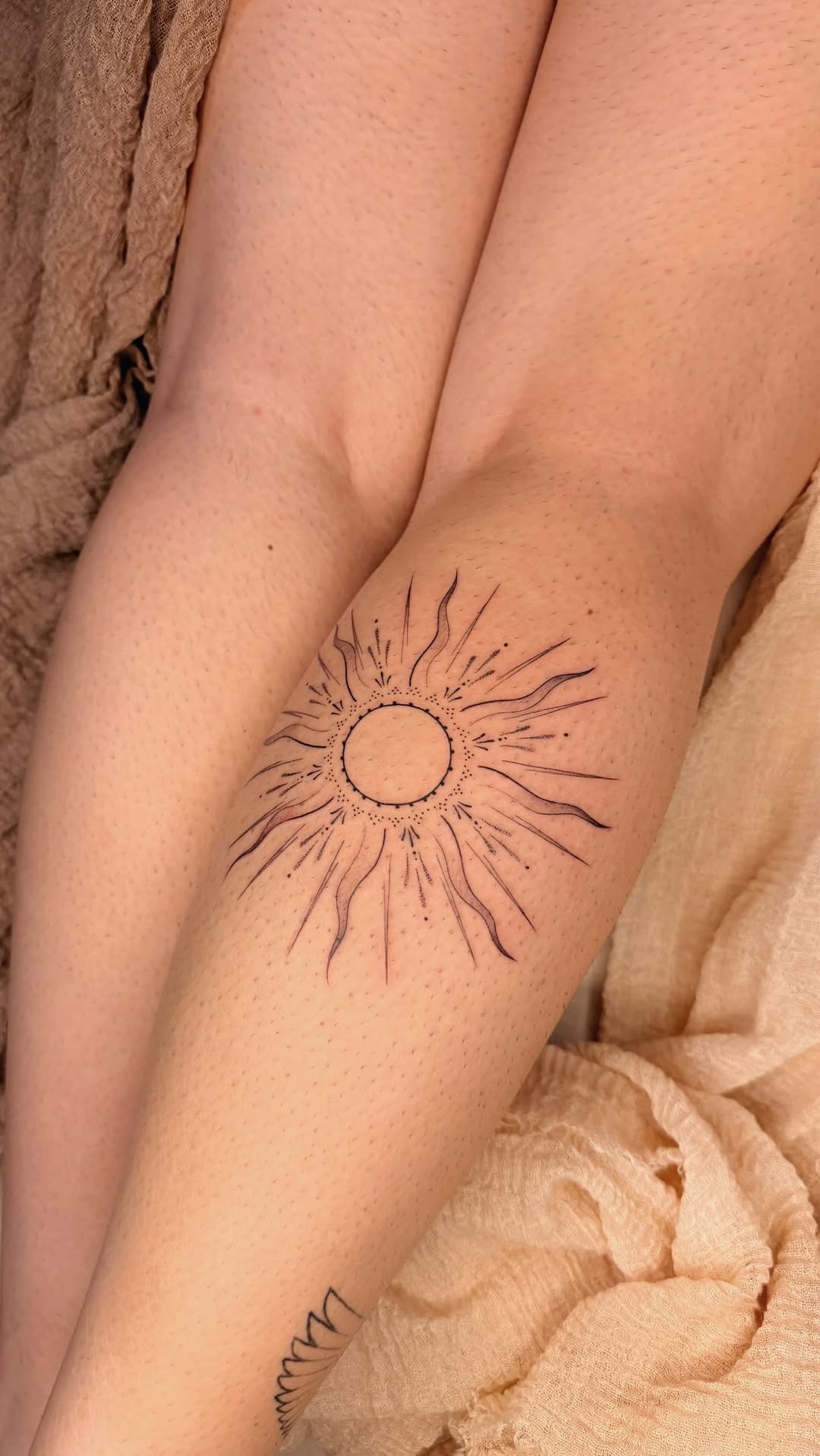 Delicate fine-line sun tattoo