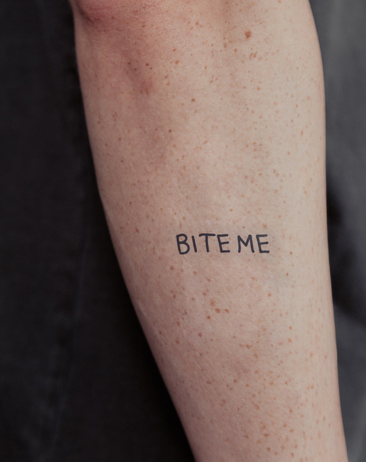 Minimalist 'bite me' forearm tattoo