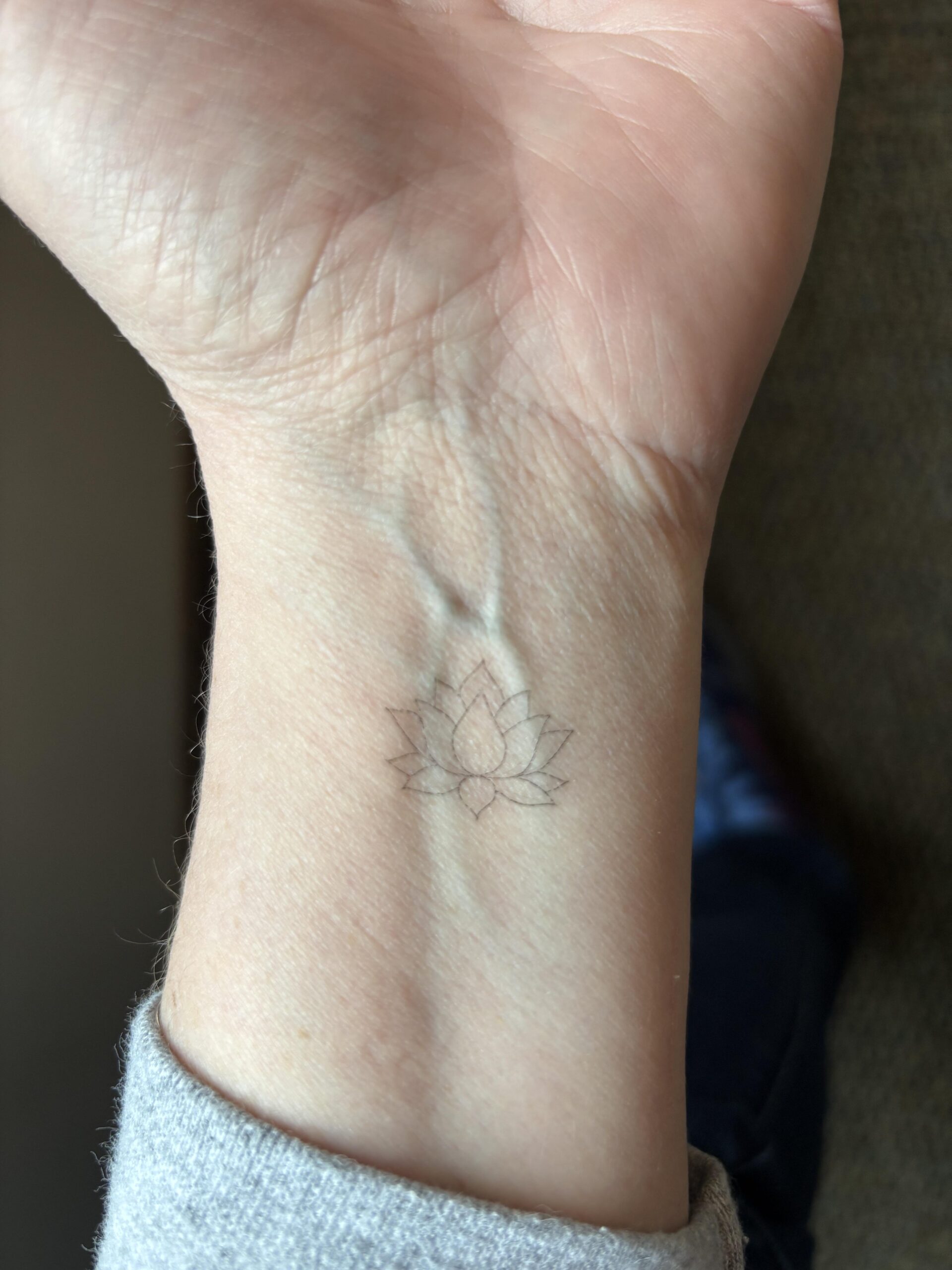 Delicate minimalist lotus wrist tattoo