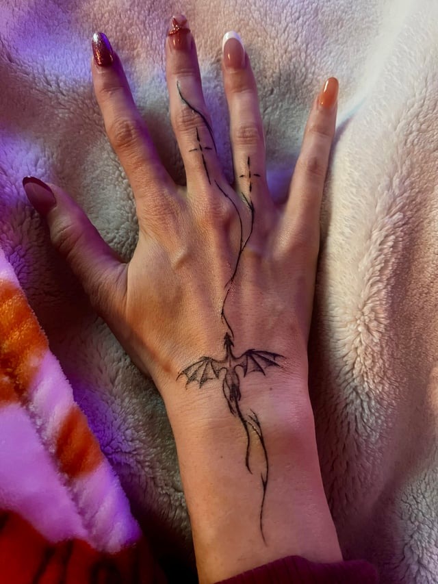 Whimsical dragon hand tattoo design