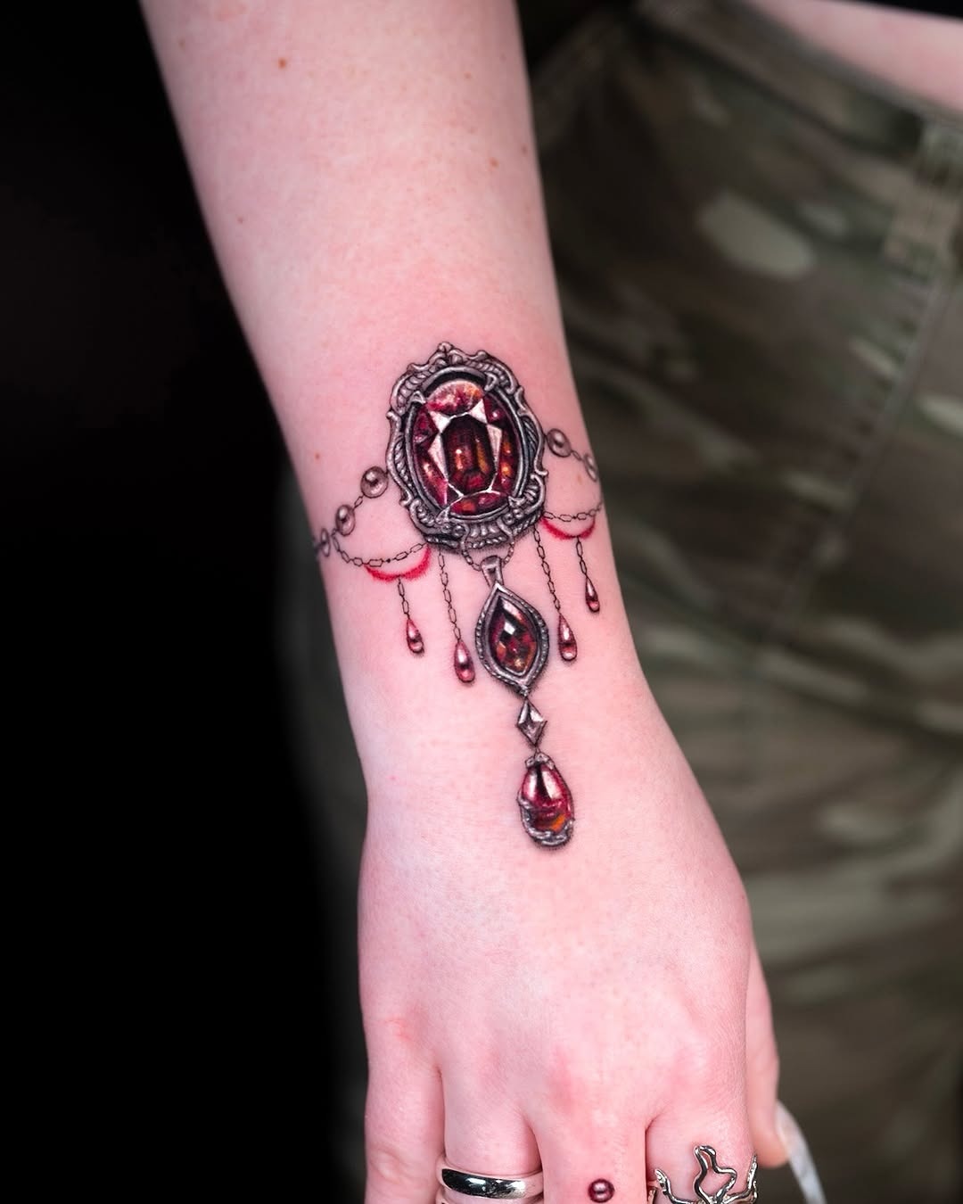 Ornate ruby-inspired wrist jewelry tattoo