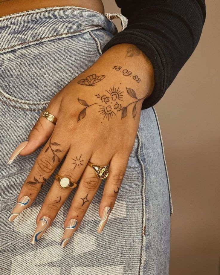 Delicate floral and star hand tattoos