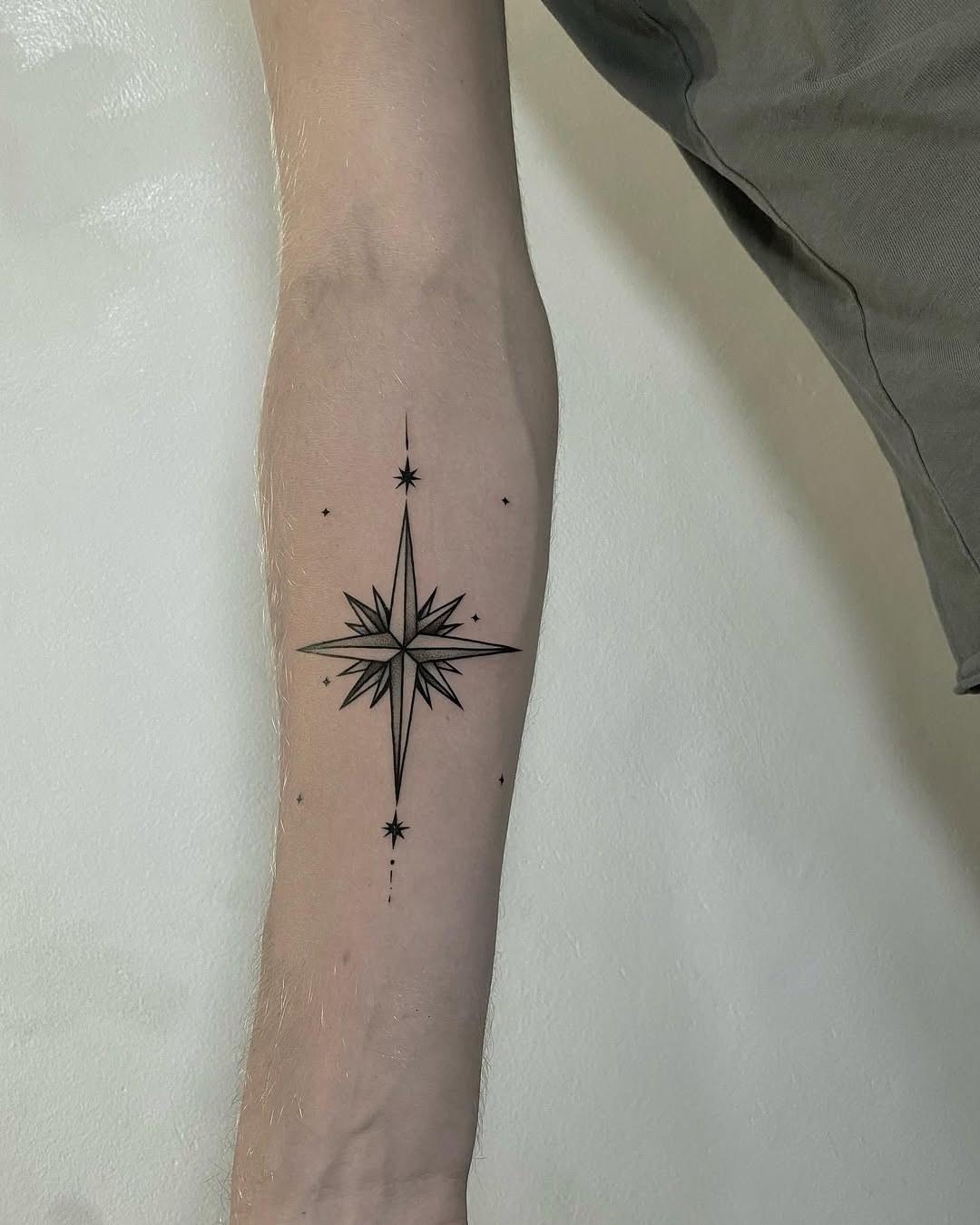 Classic fine-line compass star forearm tattoo