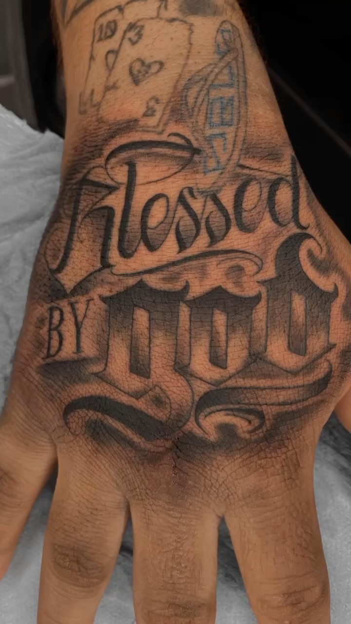 Bold hand tattoo featuring spiritual lettering